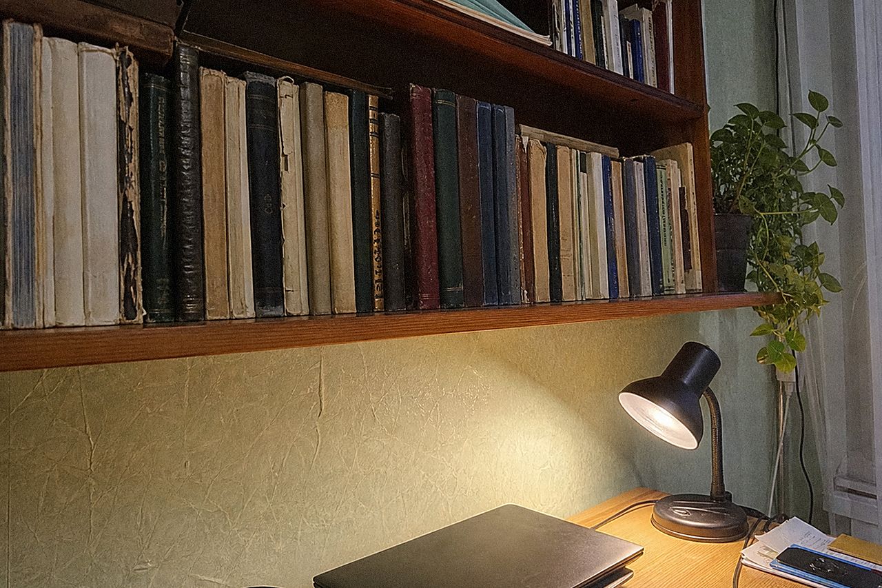 Книжная полка со старыми книгами при свете настольной лампы