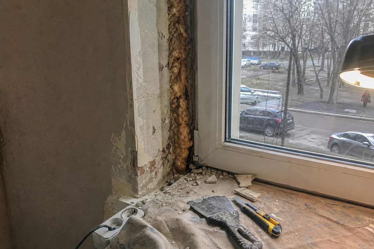Откос пластикового окна со сбитой штукатуркой, под ней потемневшая сырая монтажная пена